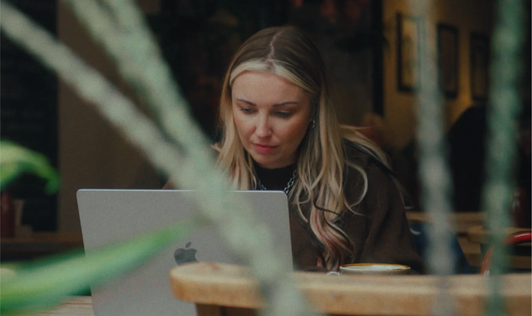 Kitty focused on her laptop in a cozy café, creating content for her podcast and fashion platform.